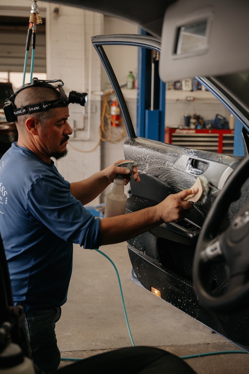 New Delta technician detailing car door panel in shop