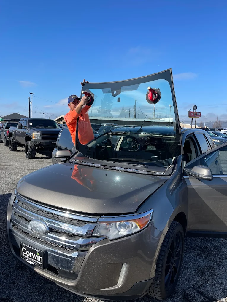 Technician installing windshield on Ford Edge with suction cups at dealer lot